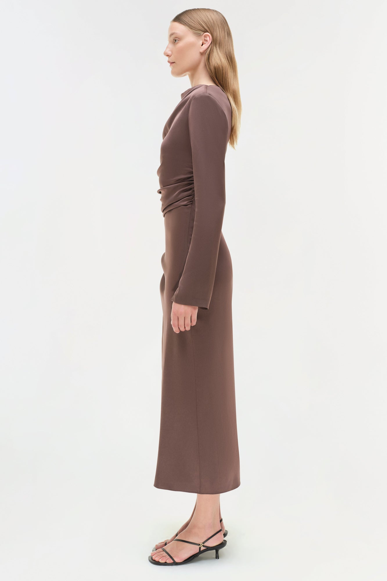 Brown satin midi dress with long sleeves and ruched side detail, shown on model in profile view.