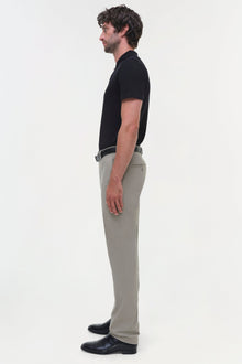 Man wearing beige cotton twill trousers with black shirt and belt, shown in side profile.