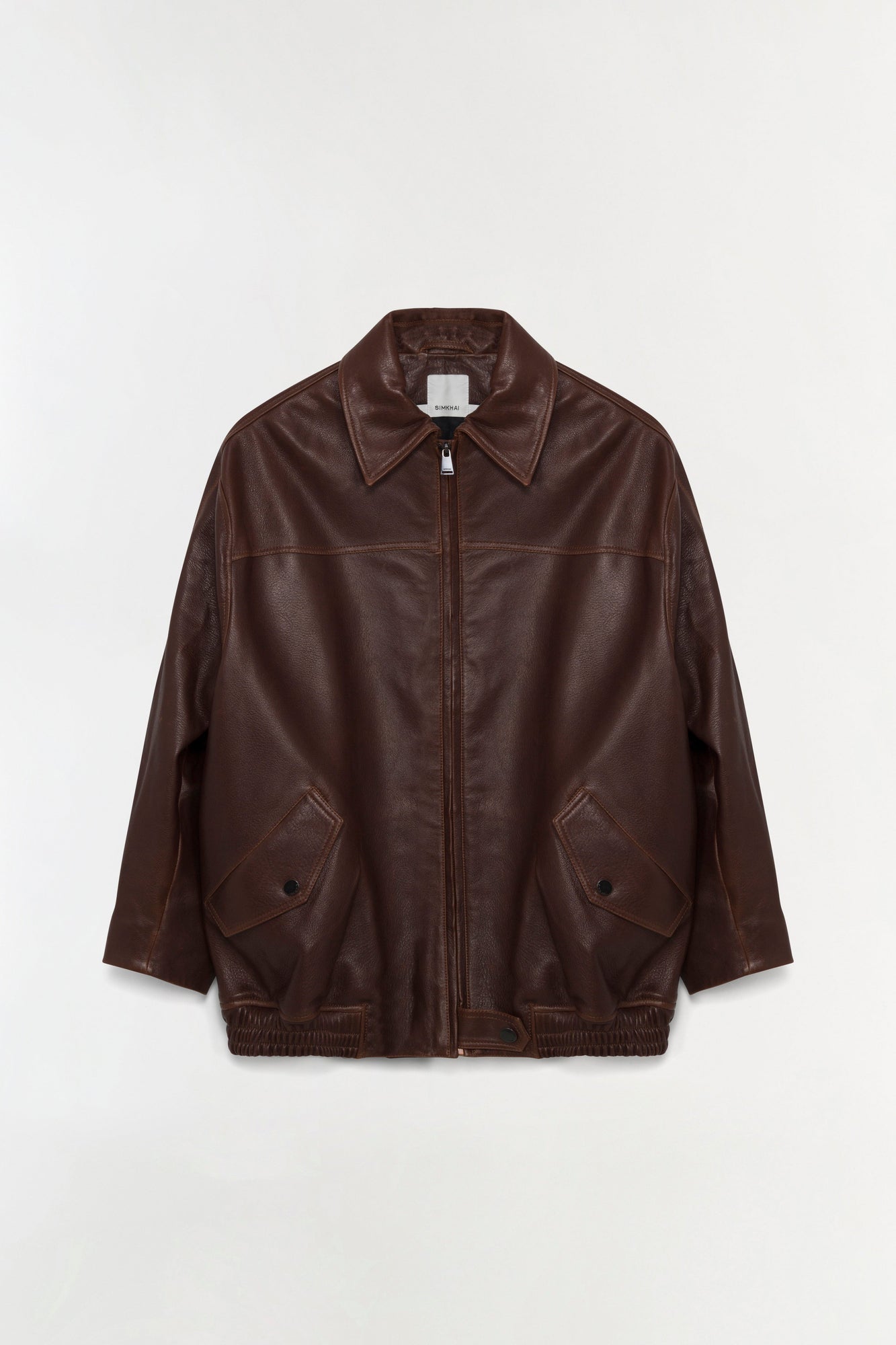 Brown leather jacket with oversized fit, collared neckline, front zip closure, and patch pockets.