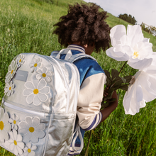 girl holding flowers wearing 3d daisies backpack