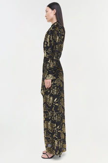 Black long-sleeve gown with gold foliage pattern, fitted silhouette, worn with black sandals.