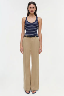 Beige wide-leg trouser with pleated front, worn with navy striped tank top and belted waist.
