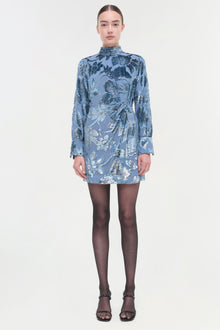 Blue floral wrap dress with long sleeves and high neckline, worn with black tights and strappy sandals.