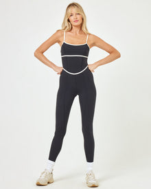 Front view of model wearing the Ace Jumpsuit in black-cream showing the full length silhouette with cream contrast detail.