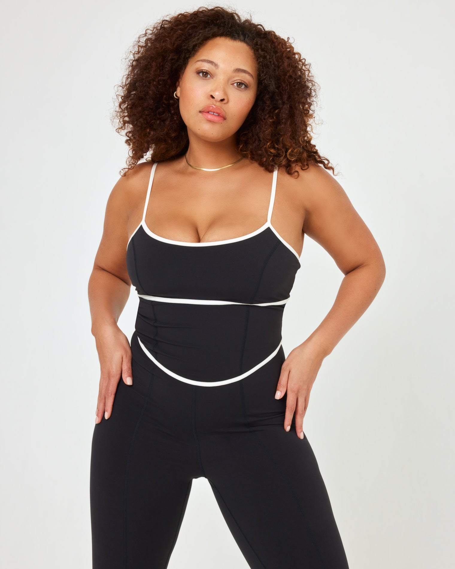 Close-up view of model wearing the Ace Jumpsuit in black-cream in XL showing the cream contrast piping and cutout detail.