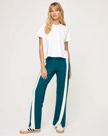 Front view of model wearing the Back To Back Pant in deep teal-cream with matching deep teal-cream Back To Back Jacket and white sneakers.