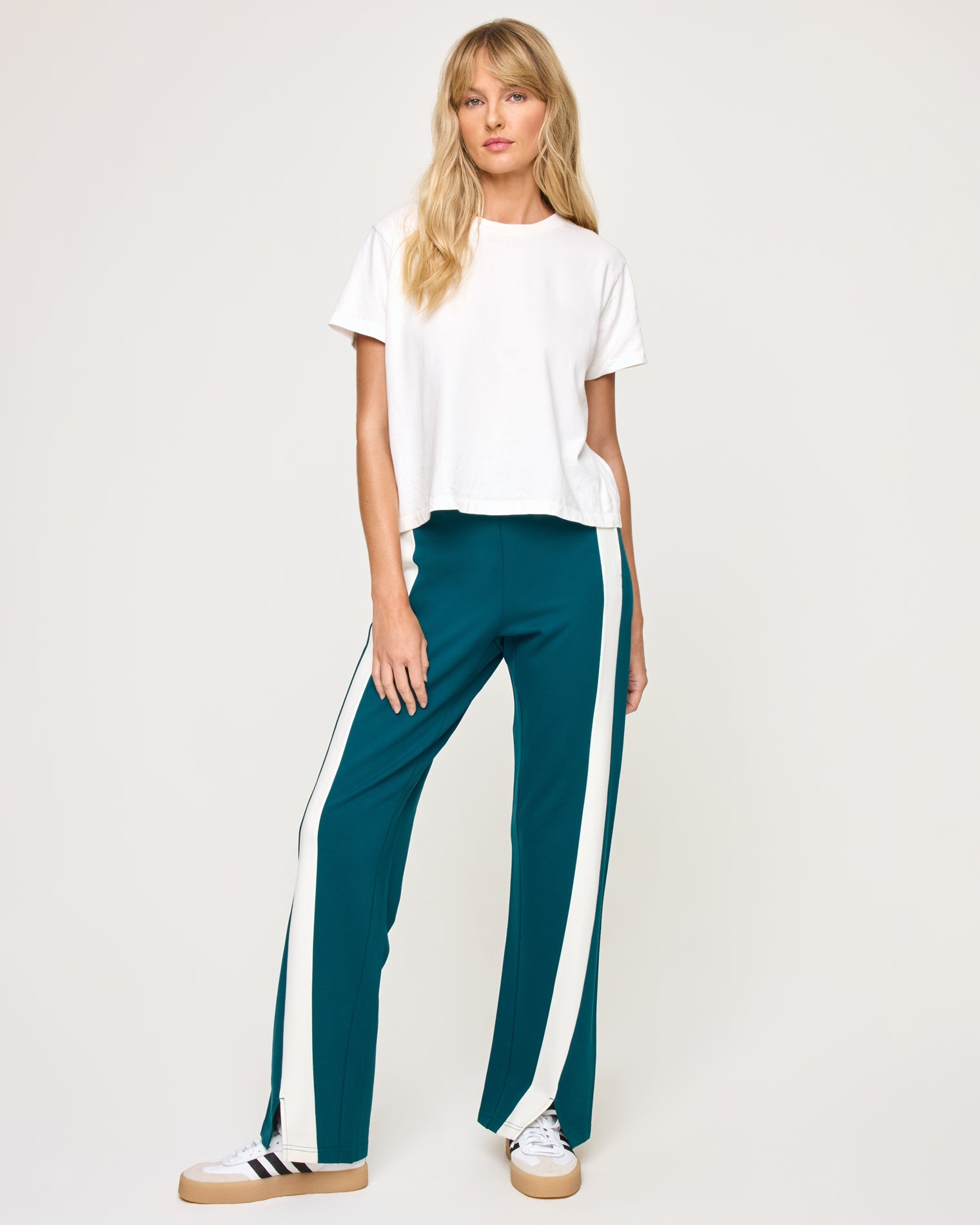 Front view of model wearing the Back To Back Pant in deep teal-cream with matching deep teal-cream Back To Back Jacket and white sneakers.