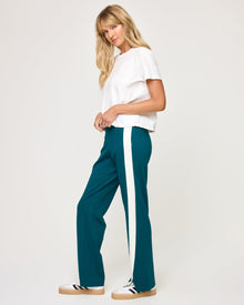 Side view of model wearing the Back To Back Pant in deep teal-cream showing the cream contrast side stripe, with matching Back To Back Jacket.