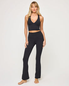 Front view of model wearing the Declan Legging in black with black v-neck crossback crop top, barefoot.