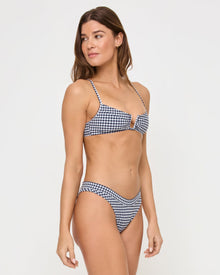 side view of woman wearing blue and white gingham bikini in front of a white background