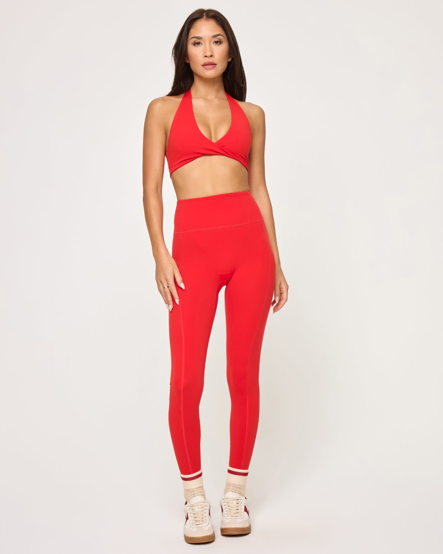 Front view of model wearing the Jeanne Bra in flame with matching flame Level Up Legging, striped socks and sneakers.