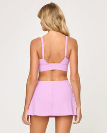 Back view of the LSPACE Unmatched Bra in mauve on a model against a white background, showing the back strap detail of the mauve crossover bra, paired with the matching mauve active skort.