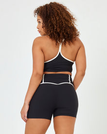 Back view of model wearing XL in the Revel Short in black-cream showing the cream piping on the waistband, with matching black-cream Revel Top.