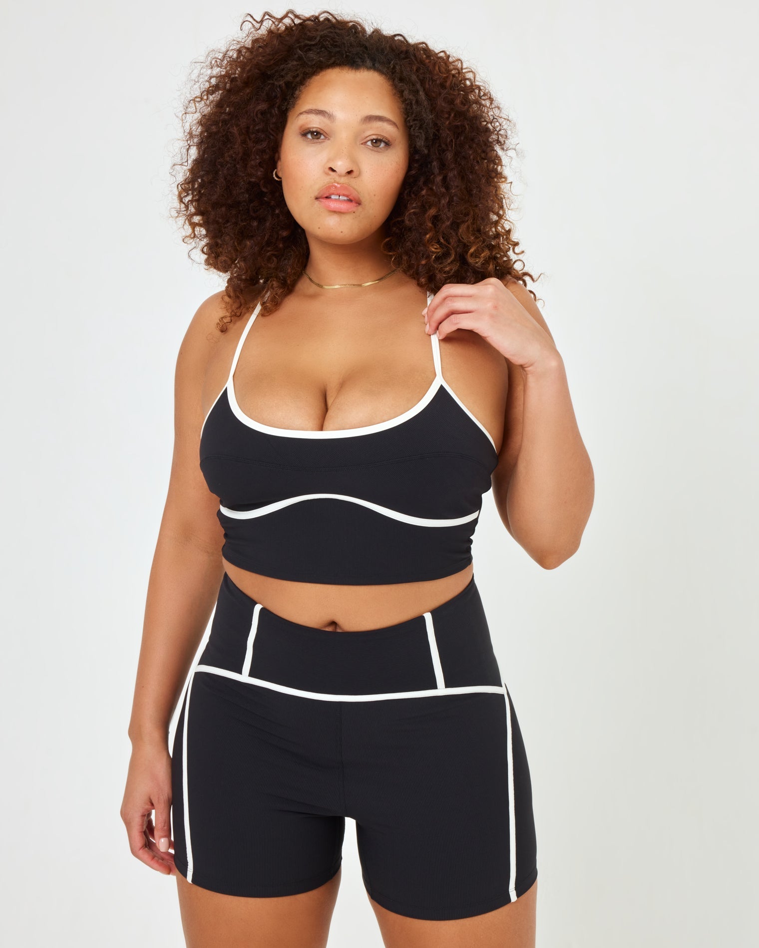 Close-up front view of model wearing XL in the Revel Short in black-cream showing the high-waist and cream piping detail, with matching Revel Top.