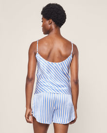 With short curly hair, a person wears the elegant Petite Plume Womens Silk Cami Short Set in Azure Stripe, standing with their back to the viewer against a plain backdrop, embodying luxury sleepwear.