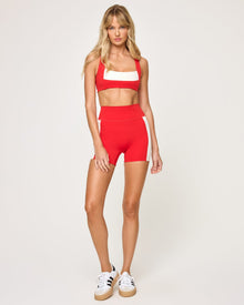 Front view of the LSPACE Uppercut Bra in flame-cream on a model against a white background, showing the square-neck sports bra with cream trim, paired with the matching flame-cream high-rise active shorts.
