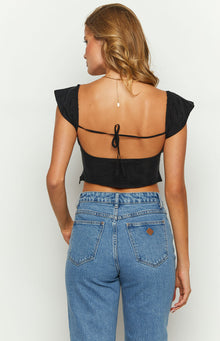 Close-up of the black top's square neckline, gathered cap sleeve, and ruched bust detail
