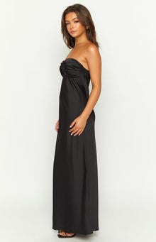 Side view of a black strapless maxi dress with a twisted ruched bust and a straight flowy skirt