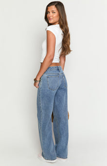 Side view of mid wash wide-leg denim jeans, showing the back pockets and relaxed silhouette