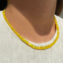 Shimmering beaded necklace made of smooth opals in shades of yellow on a gold linking ovals clasp
Styled on a neck.