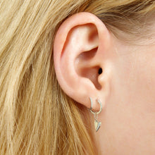 14k white gold small folded heart charm with pave diamonds on the right side. Styled on a ear hanging from a diamond pave hoop earring.