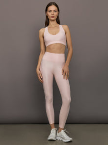 Model wears a v neck baby pink bra in a liquidy takara shine finish. 