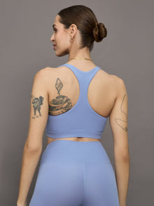 Model wears a periwinkle colored ribbed square neck sports bra with racerback detail. 