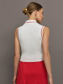 Model wears a sleeveless white tennis polo with three buttons and red seam detailing. 
