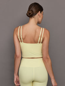 Model wears a buttery soft, ribbed pastel yellow v neck tank top. 