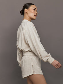 Model wears lightweight windbreaker with a snow leopard print, front zipper, and collared neck.
