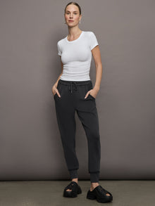 Model wears a short sleeved, ribbed jersey fitted white top with ruching down both sides. 