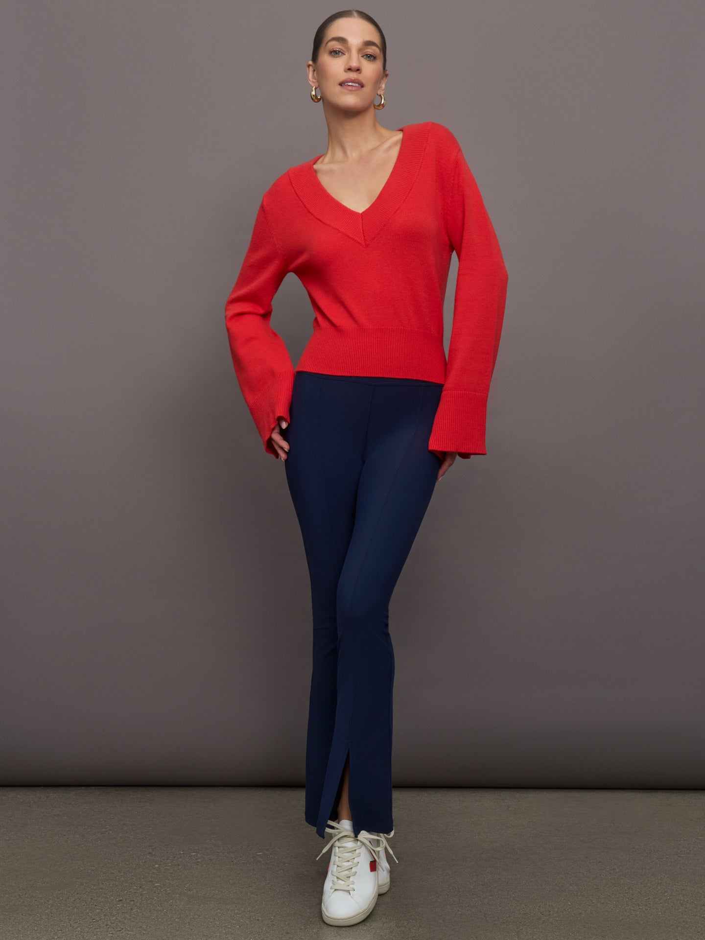 Model wears red off-shoulder sweater with bell sleeve.