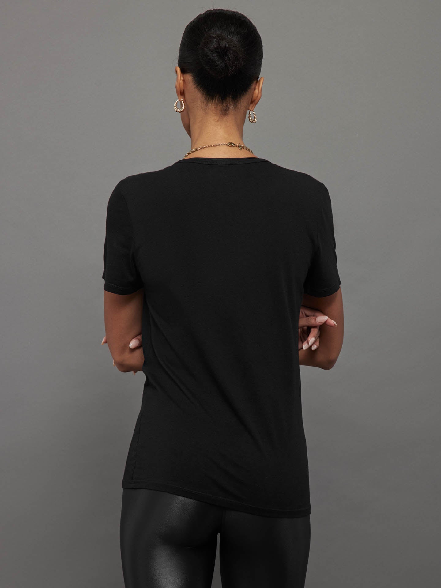 Model wears a black, short sleeve crewneck t-shirt with a front pocket and a relaxed, hip-length fit.
