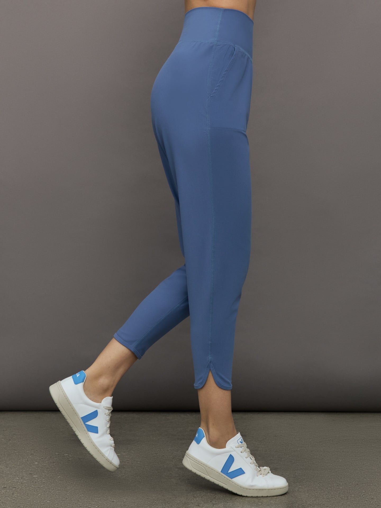 Model wears a pair of lightweight blue joggers with a wide waistband and pockets. 