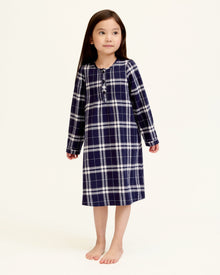 The Girl's Brushed Twill Beatrice Nightgown in Oxford Tartan features a navy, white, and gray plaid pattern, long sleeves, a round neckline, front buttons, and pleats near the chest.