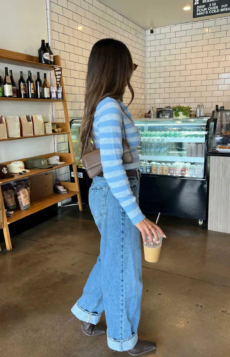 Close-up of a blue and white striped knit sweater with a partially unzipped front and cropped hem
