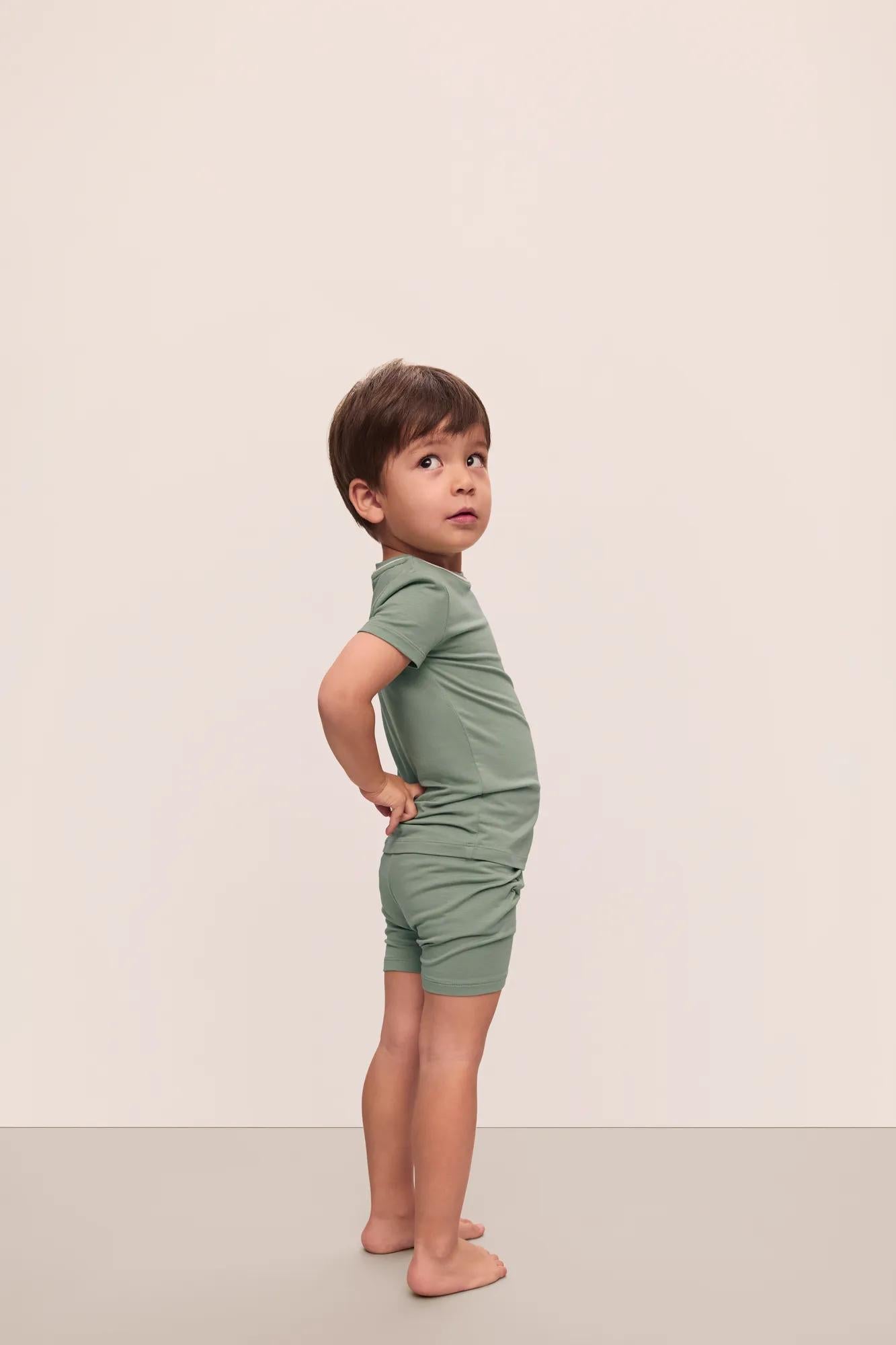 Model is wearing Kids TENCEL Modal Unisex Short PJ Set in Eucalyptus/Ivory