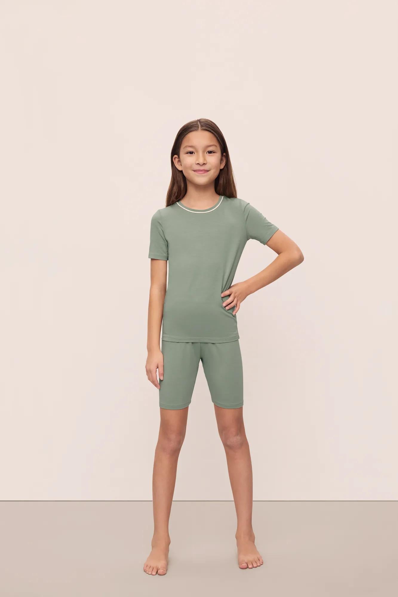 Model is wearing Kids TENCEL Modal Unisex Short PJ Set in Eucalyptus/Ivory