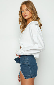 Rear view of a dark blue denim mini skirt with a straight hem and a central vertical seam