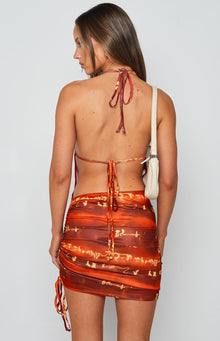 Side view of a red patterned mini dress showing the side cutouts and adjustable ruched ties