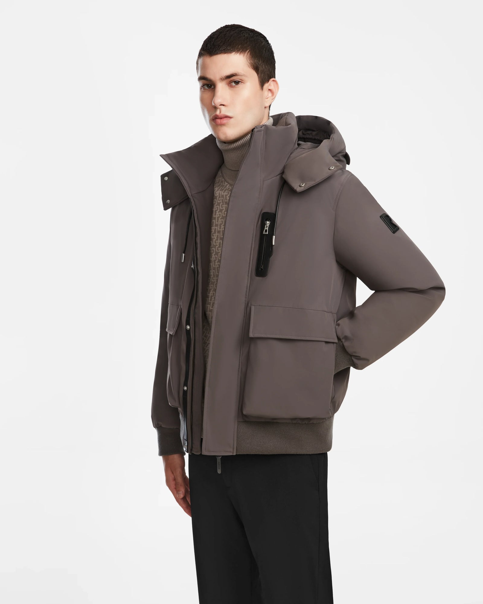 A young man with short dark hair models the Rudsak ASH - 6124599 Grey bomber jacket over a turtleneck sweater and black pants, standing against a plain white background.