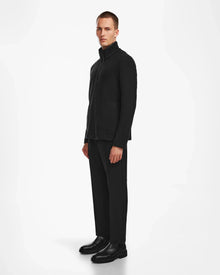 A man in a black suit wears the Rudsak BECK - 6524538 Black men’s fleece half-zip pullover, featuring stylish vegan leather trims for modern casual style.