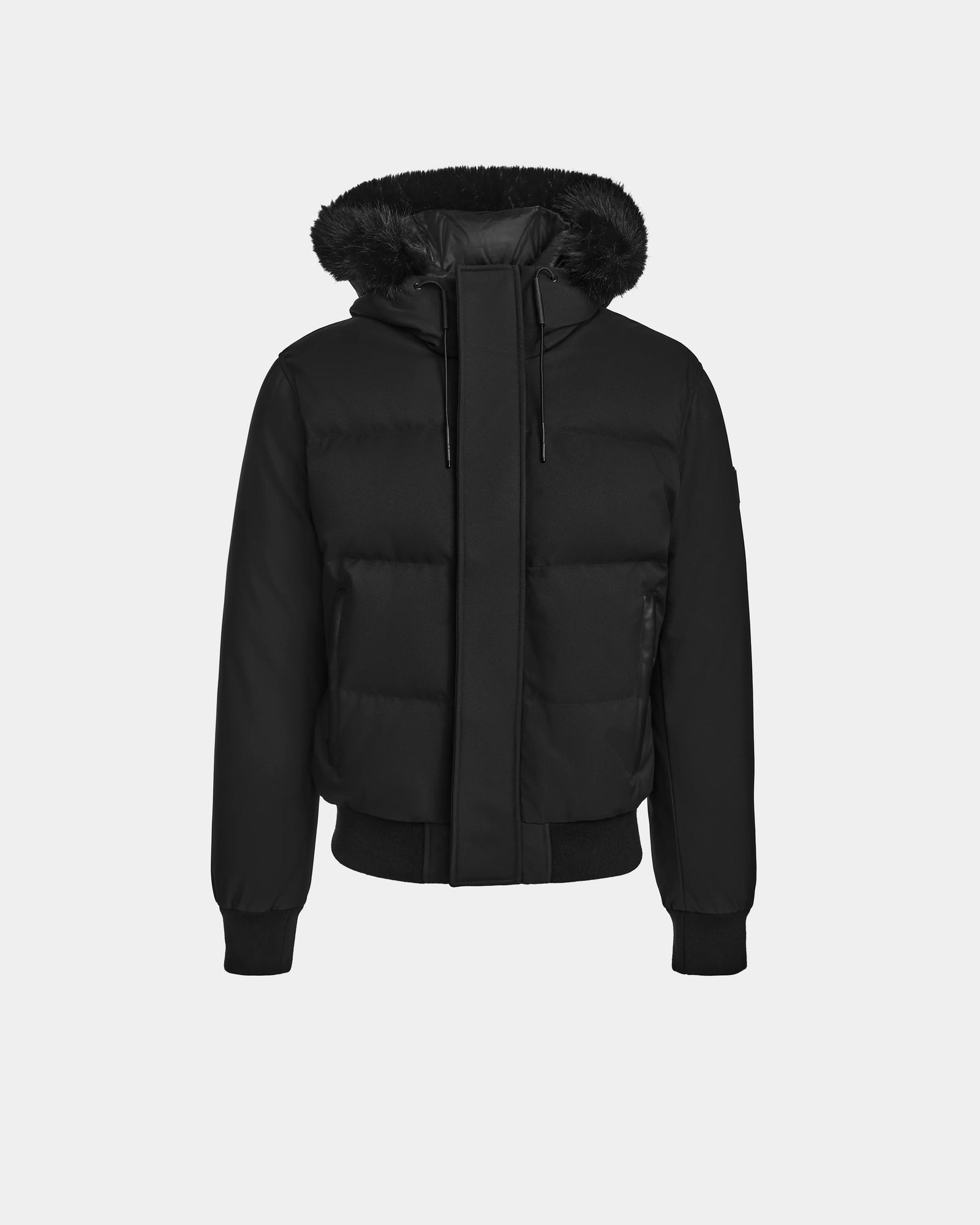 The Rudsak DALLAS - M122501 Black is a weather-resistant puffer coat with black fur-trimmed hood, flap-covered front zipper, ribbed cuffs, and ribbed waistband, shown on a plain light gray background.