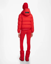 A person stands with their back to the camera, wearing the Rudsak DANI M - 8124539 Flame Red jacket and matching red winter accessories against a white background.