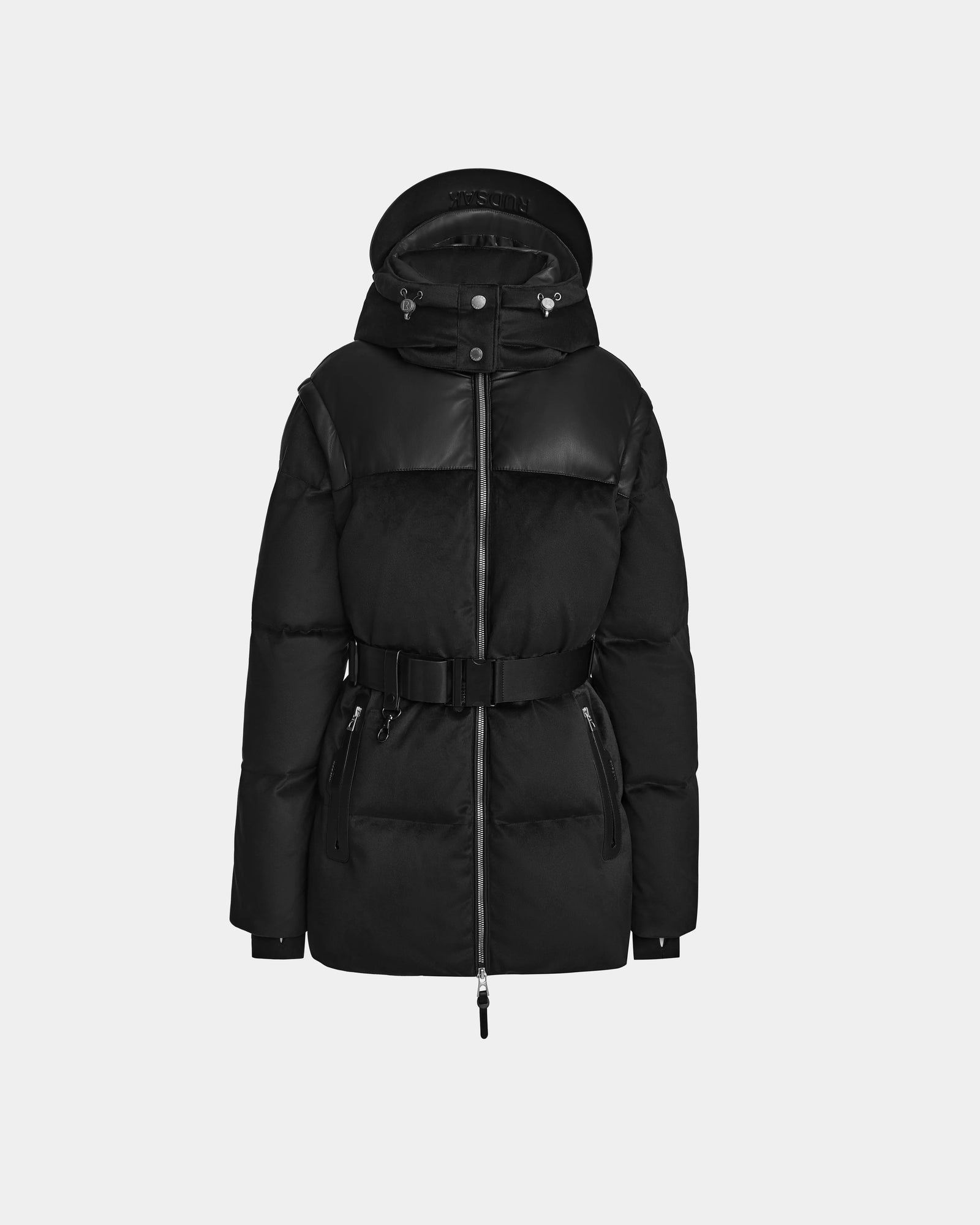 The Rudsak DONIA - L124563 Black is a women’s down puffer jacket with a belted waist, zippered front and pockets, plus leather-like shoulder and chest details, shown against a plain light gray background.