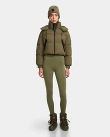 A woman faces forward in a Rudsak KARLEE - 8124721 Loden Green cropped down puffer jacket, matching leggings, knit beanie, and boots against a plain white background.