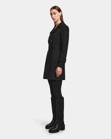 A woman in the Rudsak KIMBERLY - 8124801 Black womens belted trench coat.