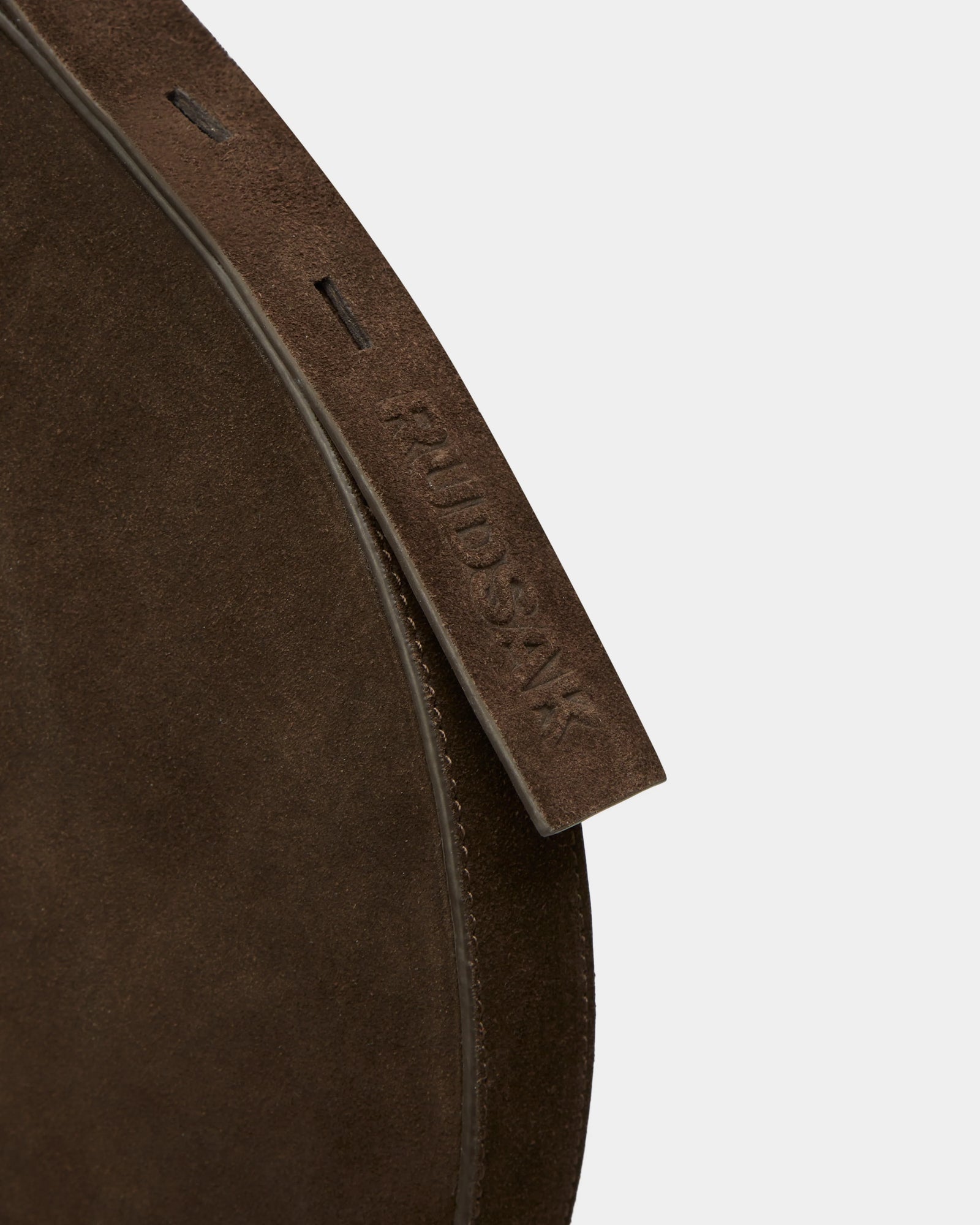 Close-up of the Rudsak LANISSA S - 8324520 Espresso, a brown suede hobo bag featuring a leather strap embossed with RUDSAK, set against a plain light grey background. This minimalist women’s crossbody bag is perfect for daily essentials.