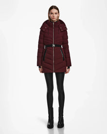 A woman stands facing forward, wearing the Rudsak MALAYA M - L123554 Wine women’s down puffer jacket, black leggings, and black ankle boots against a plain white background.