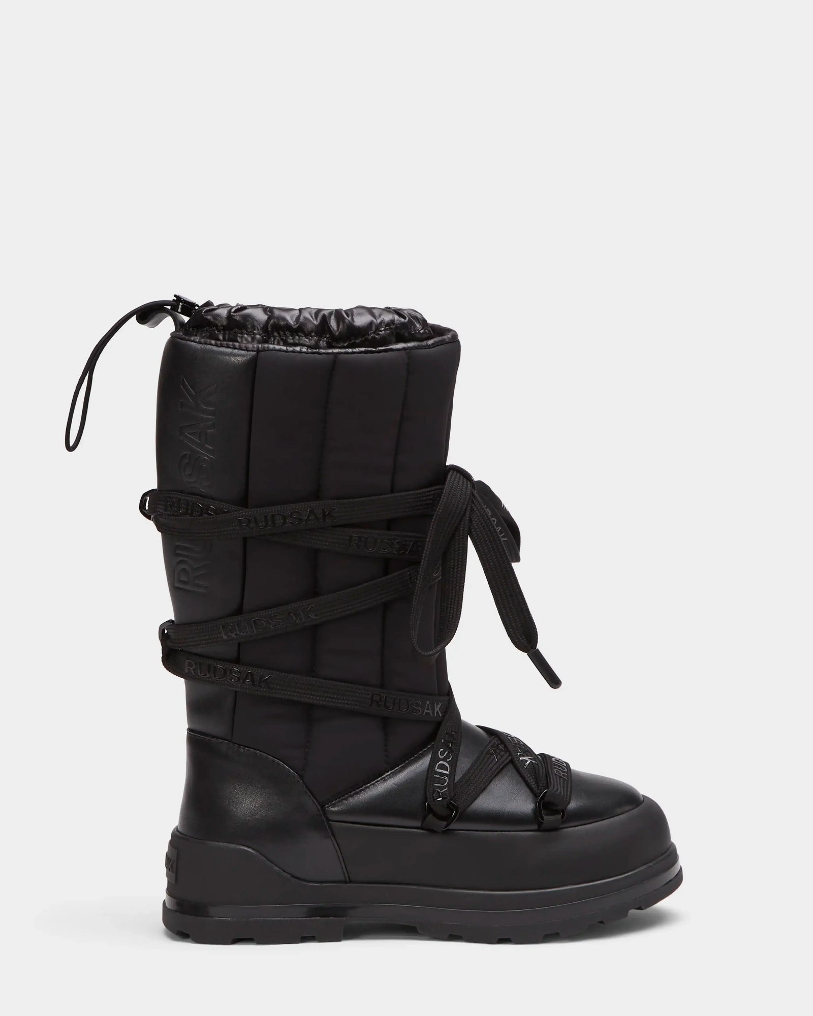 The RODIN - 8224502 Black women’s winter boot by Rudsak features a thick anti-slip sole, quilted shaft, drawstring top, crisscross laces, cozy polar fleece lining, and visible Rudsak branding on the laces and side.
